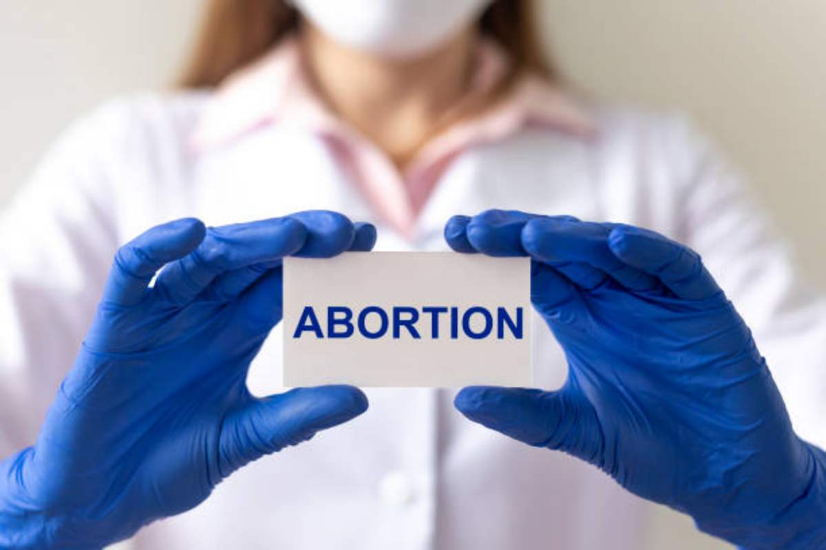 Medico con in mano un foglio con scritto "aborto"