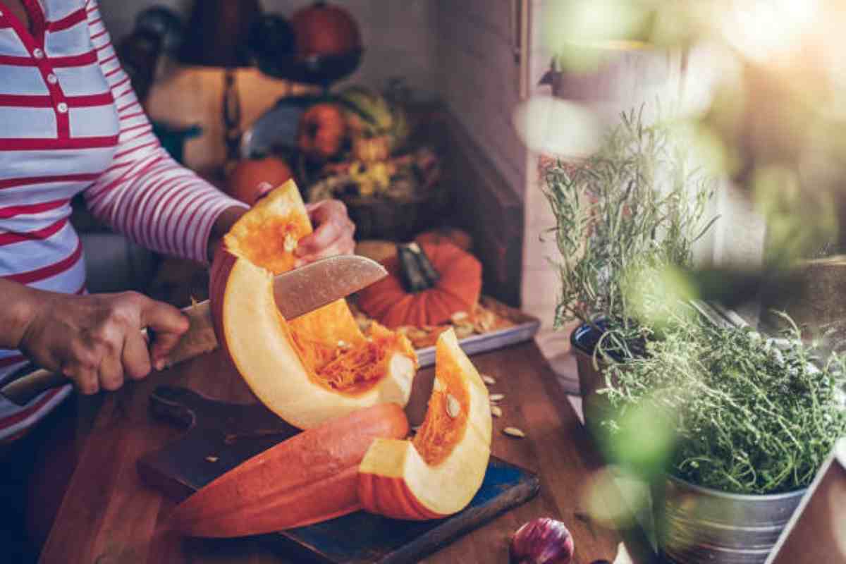 Donna taglia la zucca in cucina