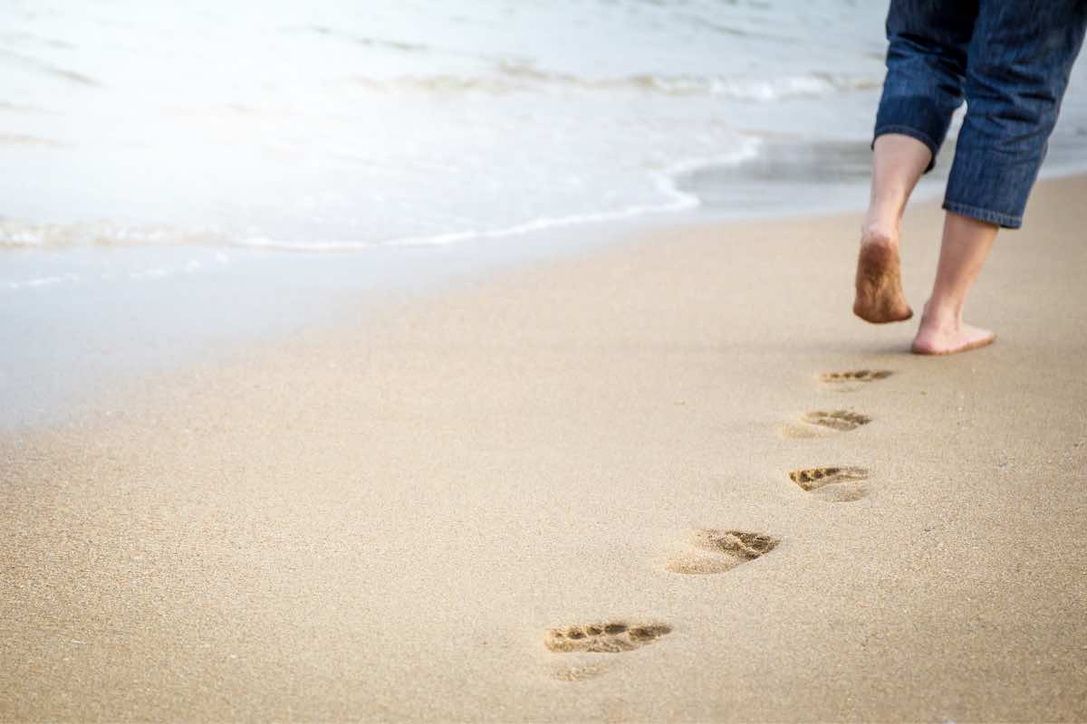 Una persona cammina sulla spiaggia
