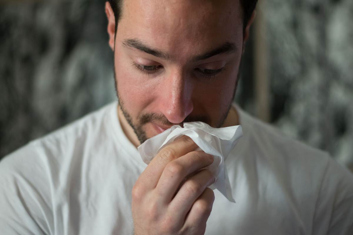 Uomo si soffia il naso per via del raffreddore
