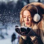 ragazza che soffia sulla neve vestita in modo pesante