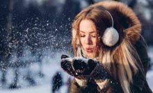 ragazza che soffia sulla neve vestita in modo pesante